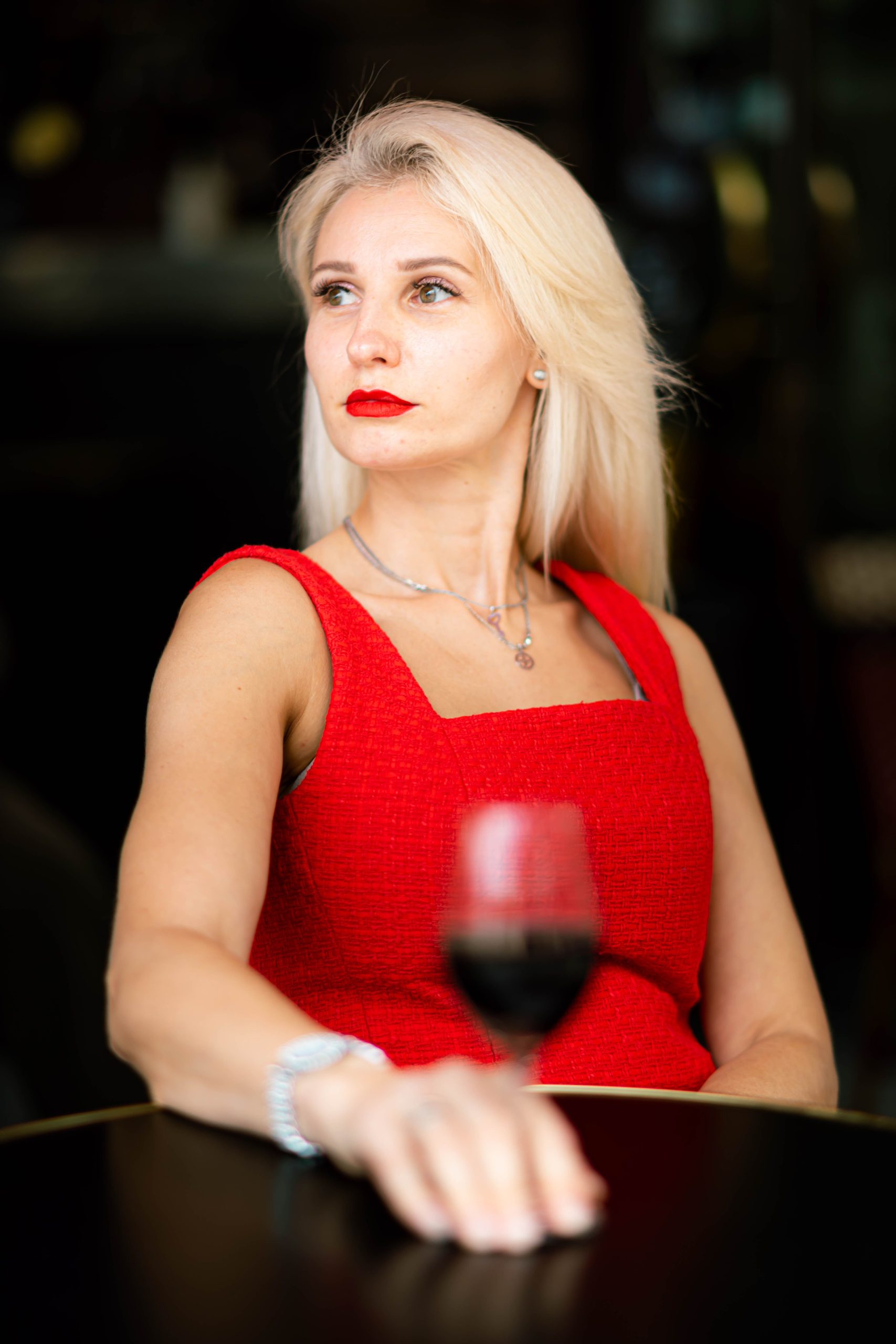 Elegant woman in a red dress enjoying a glass of wine, symbolizing refined companionship