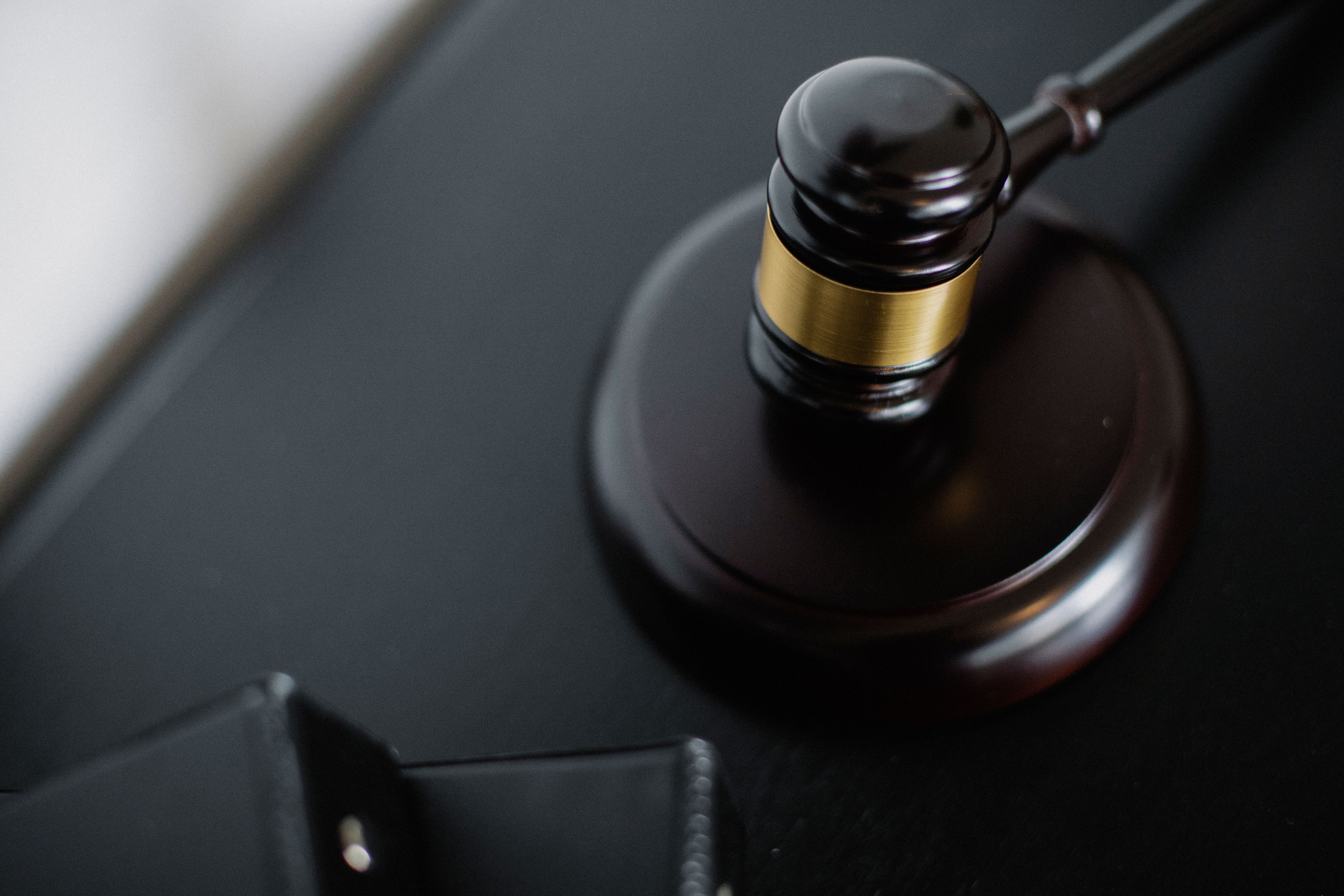 Wooden gavel beside legal folders on a courtroom table