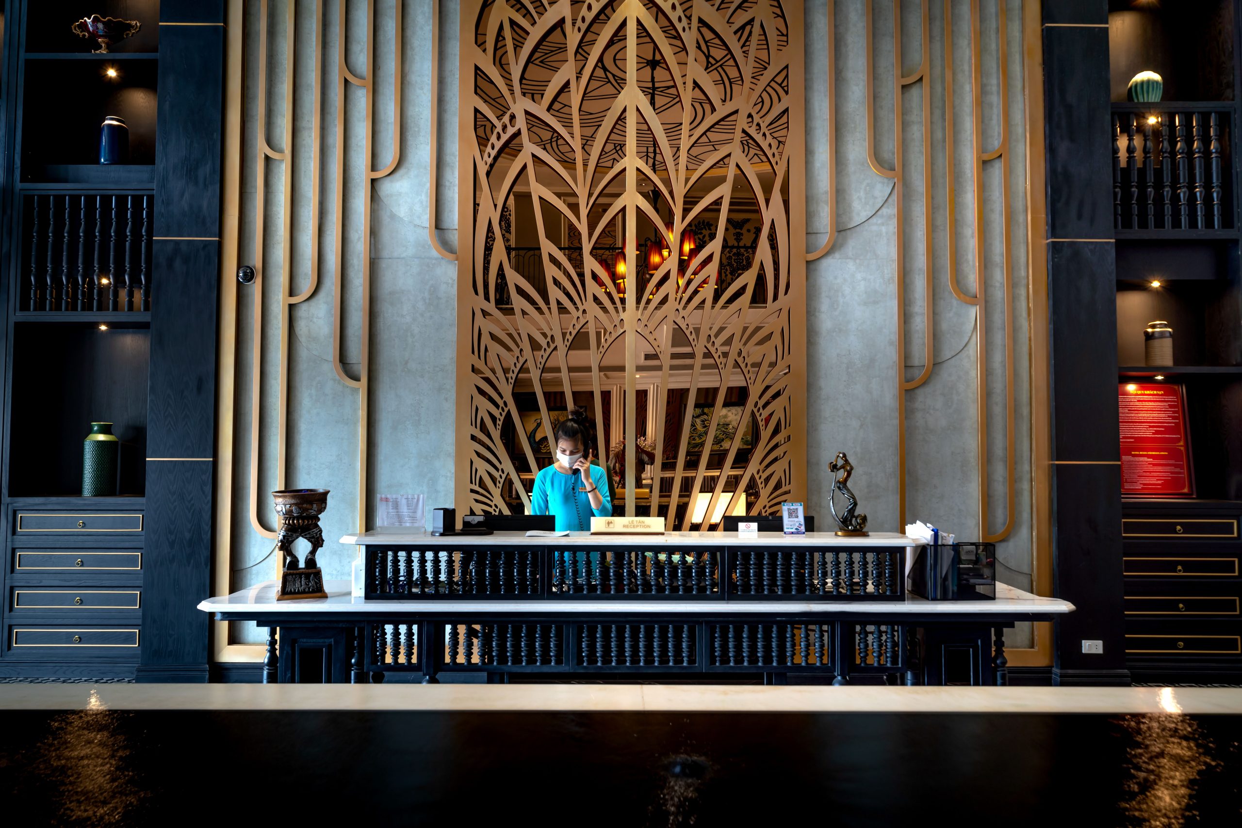 Luxurious hotel reception area with intricate design and a receptionist at work.