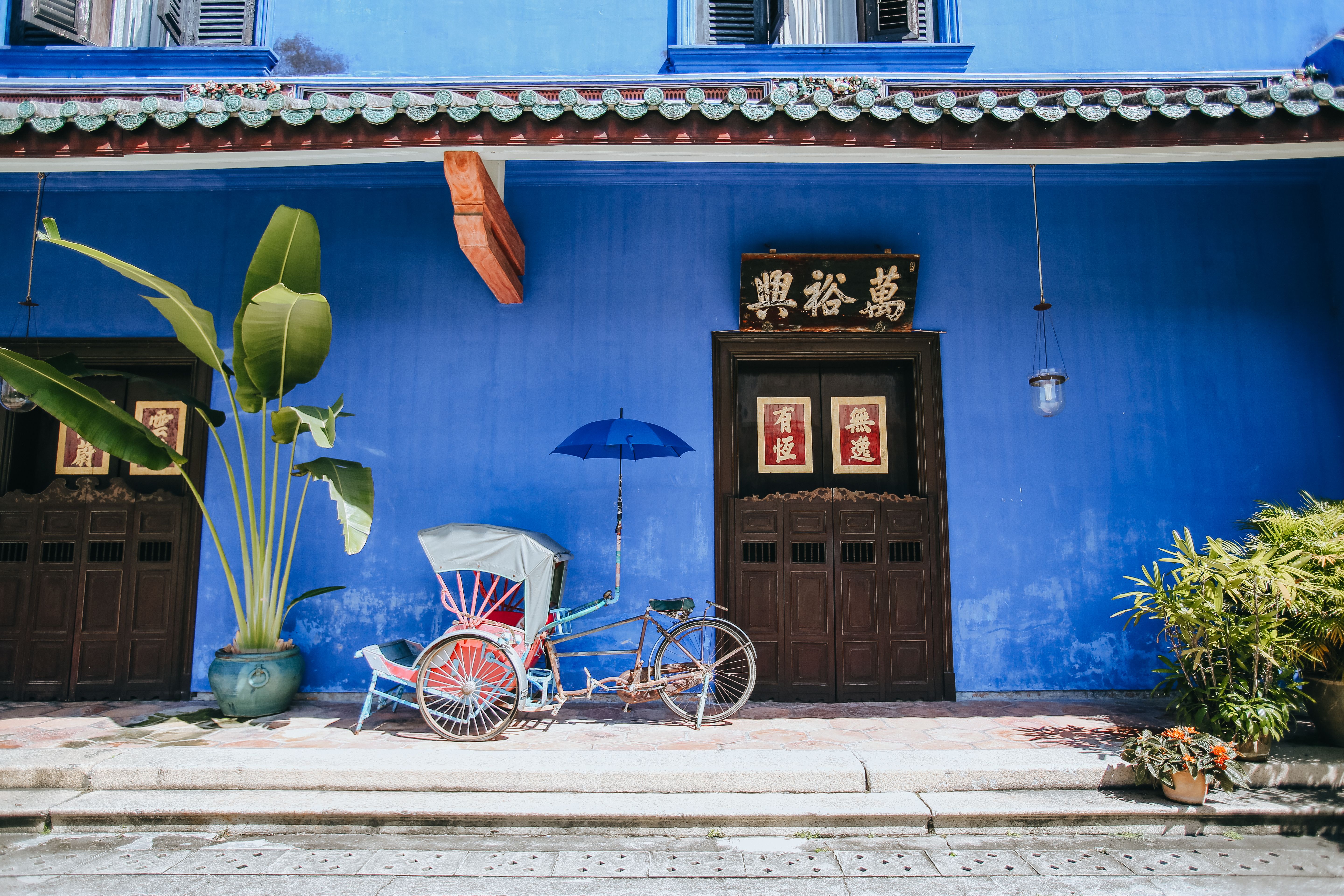 Traditional rickshaw in front of a blue facade in George Town, Penang