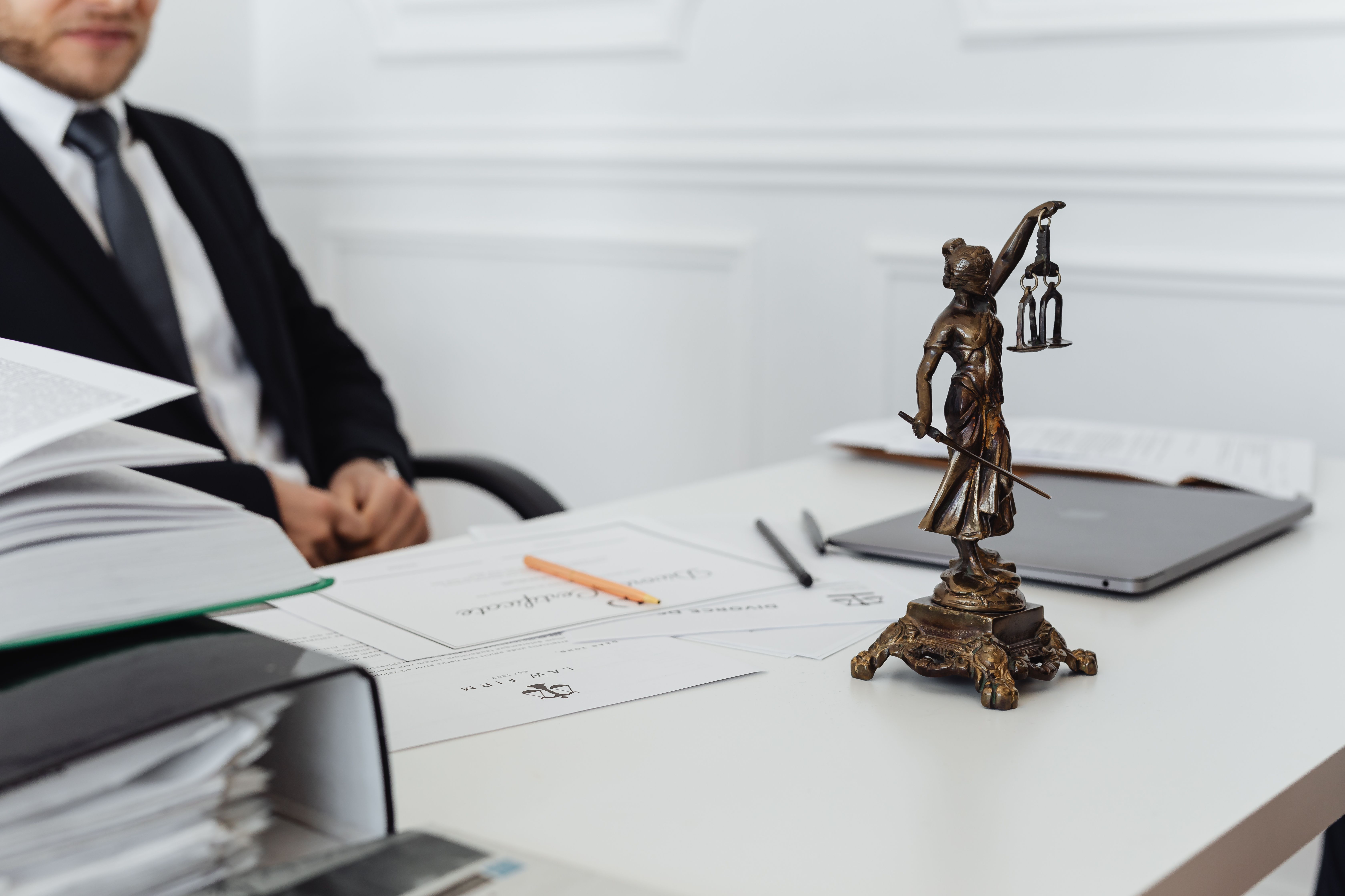 Legal professional workspace with documents, laptop, and Lady Justice statue
