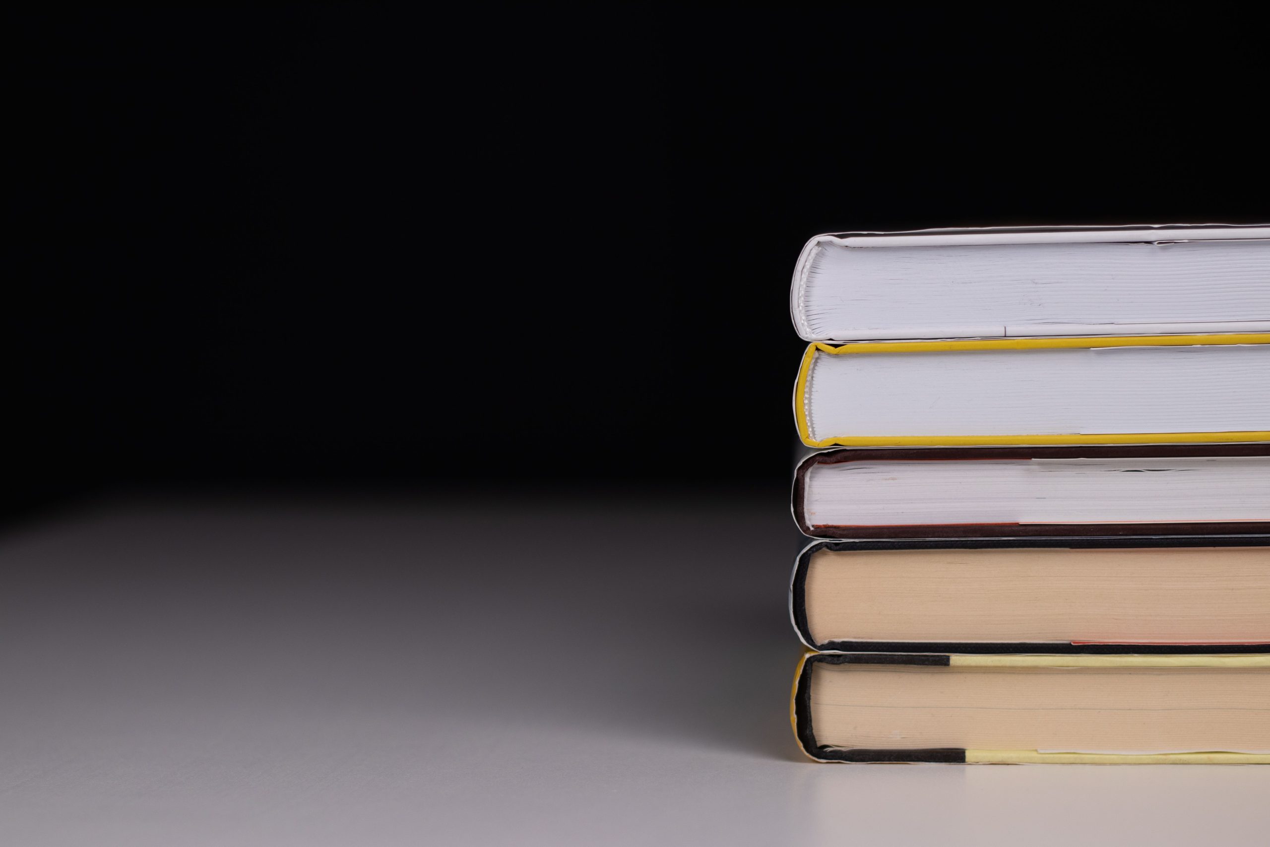 Minimalist stack of hardcover nonfiction books on a dark background, illustrating political scandal reading
