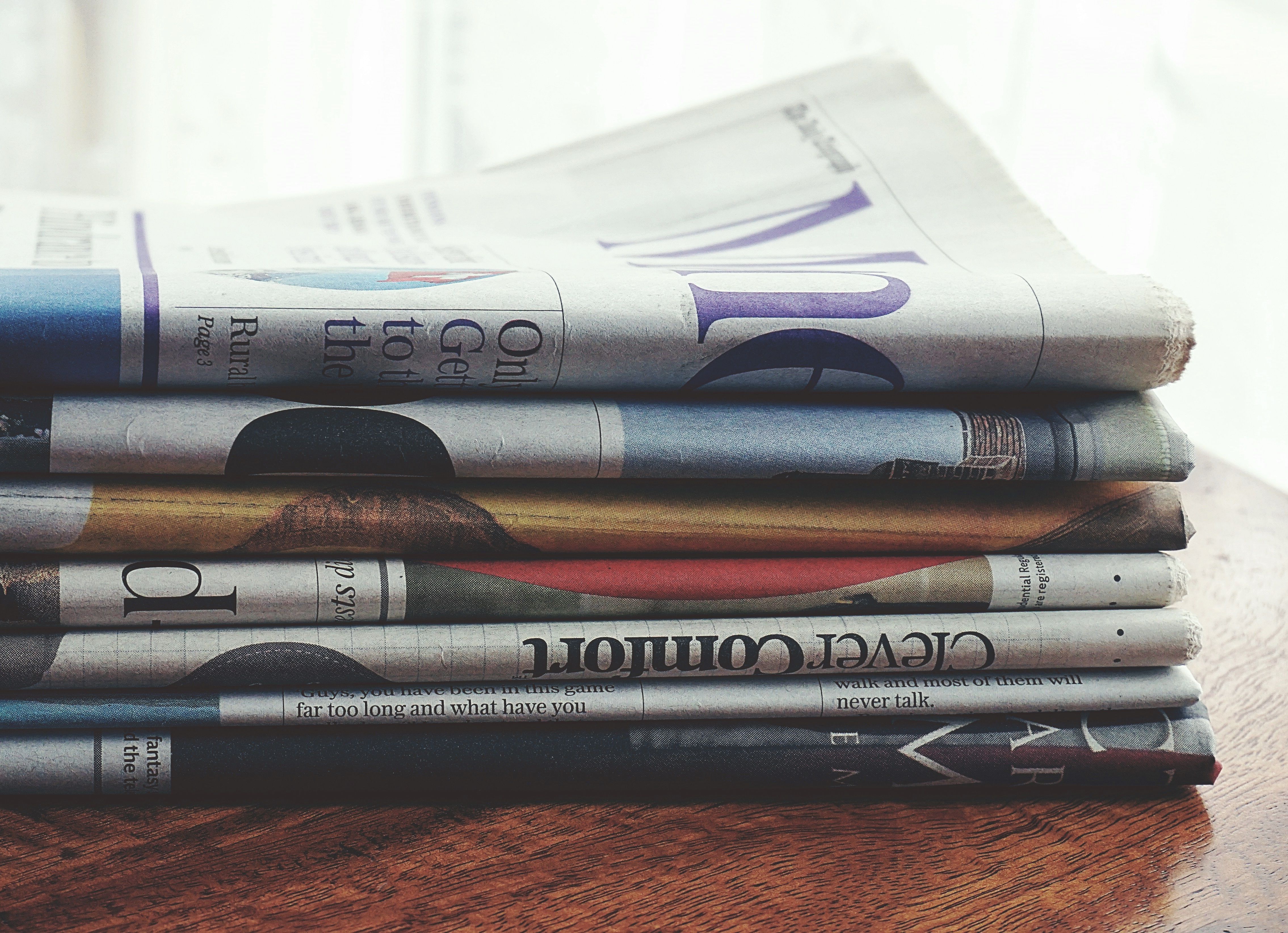 Stack of folded newspapers on a wooden table symbolizing political scandal headlines