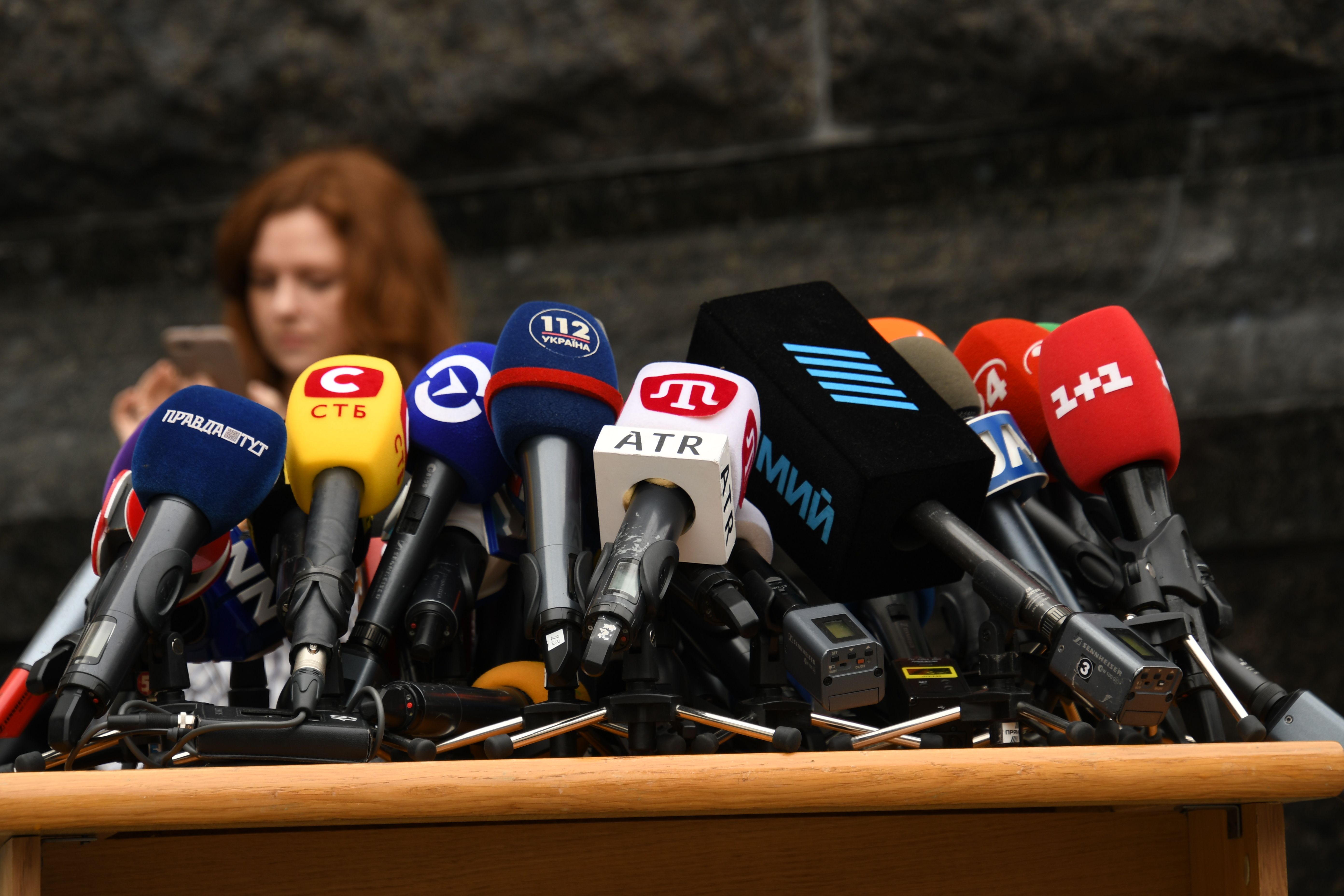 Cluster of microphones at a press conference representing media coverage of political scandals